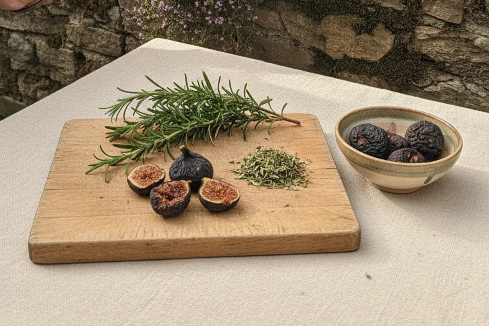 Kräutergarten an einer alten Natursteinmauer, Hände ernten einen Rosmarinzweig